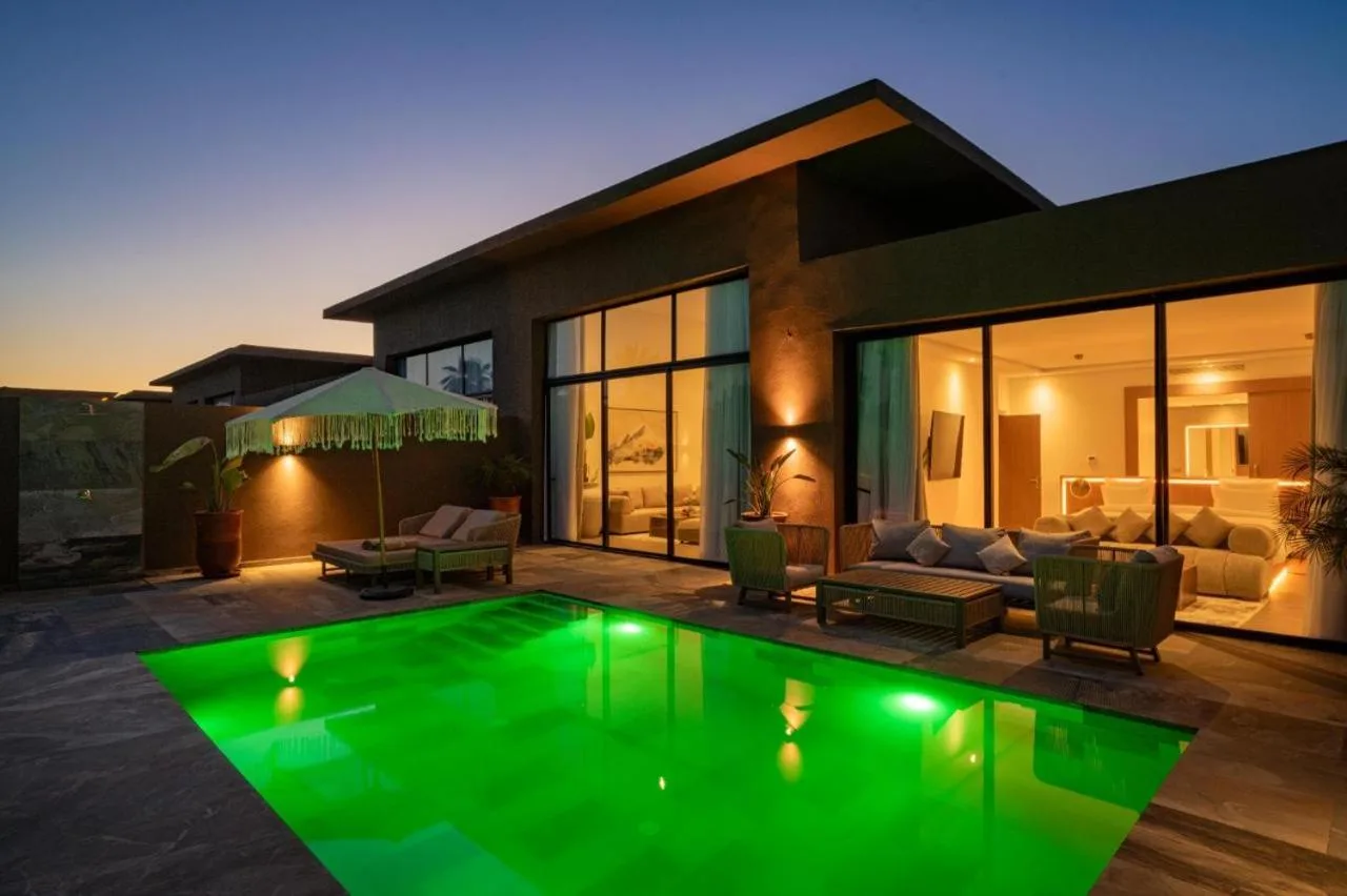 NOMMOS Beach RESORT & POOL CLUB – Hotel in Marrakesch, Marokko – ein Haus mit einem grünen Pool davor im NOMMOS Beach RESORT & POOL CLUB in Marrakesch