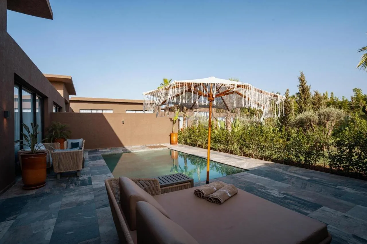 NOMMOS Beach RESORT & POOL CLUB – Hotel in Marrakesch, Marokko – ein Swimmingpool mit einem Sofa und einem Sonnenschirm im NOMMOS Beach RESORT & POOL CLUB in Marrakesch