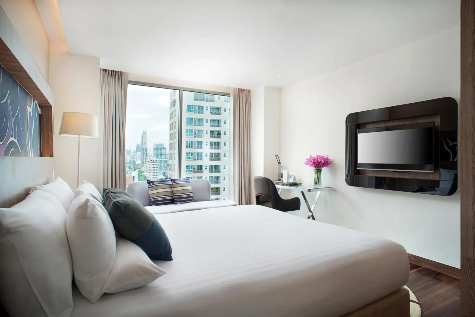 Novotel Bangkok Sukhumvit 20 – Hotel in Bangkok, Thailand – ein Mann, der in einem Stuhl in einem Zimmer mit einem Fenster im Novotel Bangkok Sukhumvit 20 in Bangkok sitzt