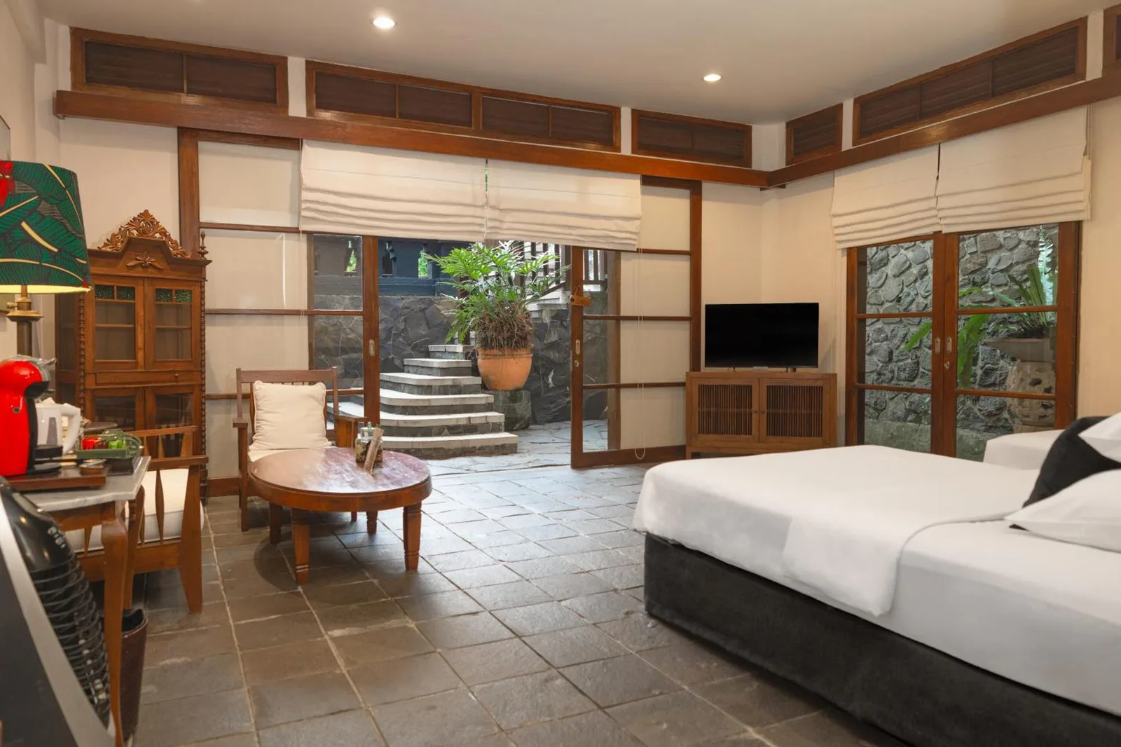 Chambre confortable au Novus Giri Resort & Spa à Sukabumi avec un lit, une télévision et un accès extérieur.