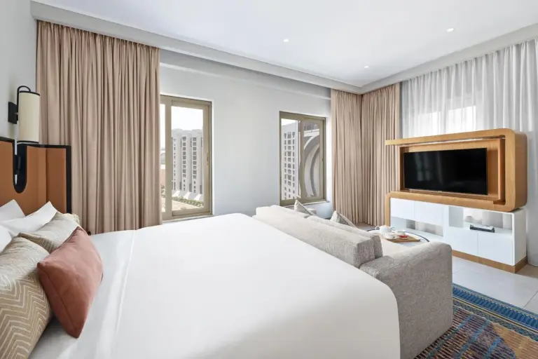 Bedroom with seating area and television inside Oaks Ibn Battuta Gate Dubai hotel suite