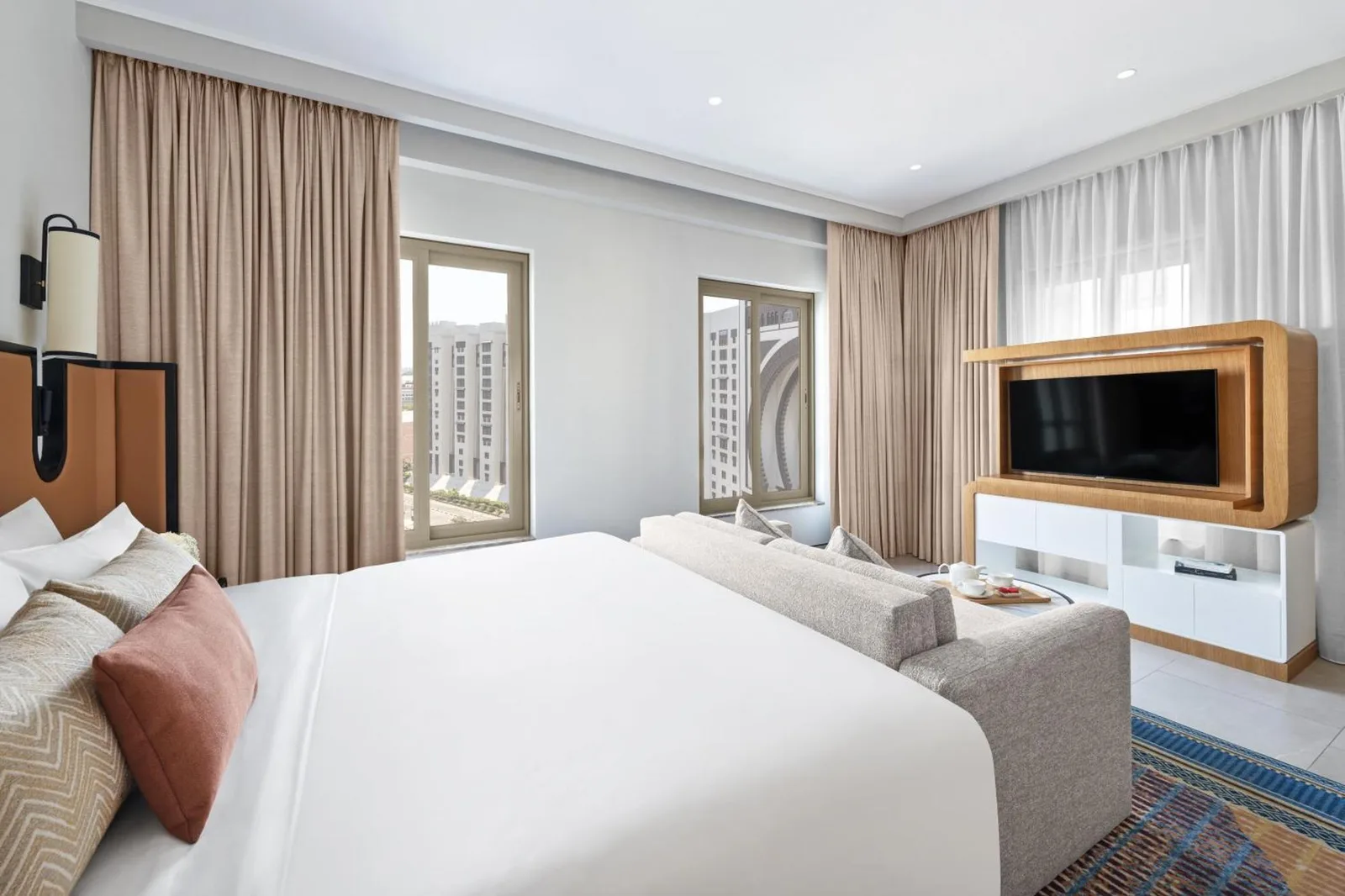 Bedroom with seating area and television inside Oaks Ibn Battuta Gate Dubai hotel suite