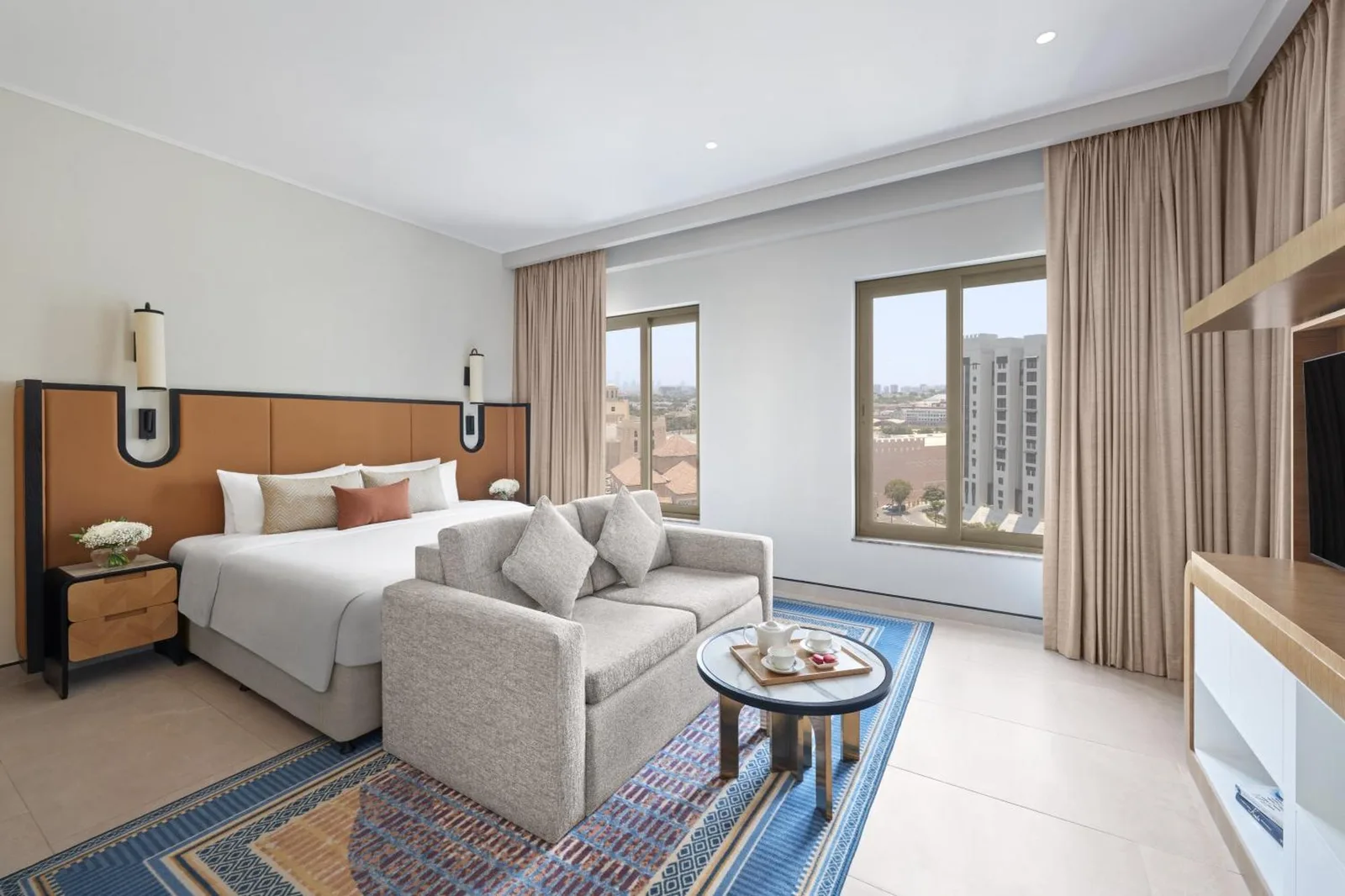 Suite bedroom at Oaks Ibn Battuta Gate Dubai with sofa seating and panoramic windows
