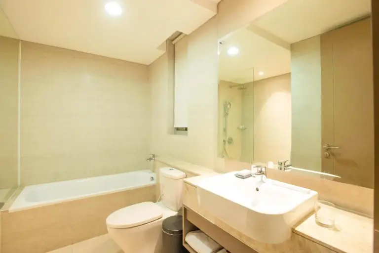 Zona de baño relajante con bañera en el apartamento de Oakwood PIK Jakarta.