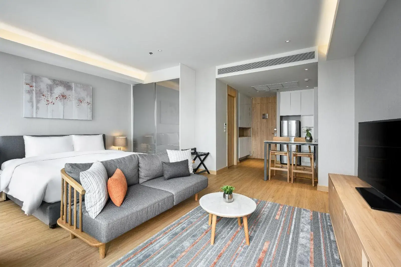 Oakwood Suites Bangkok – Hotel in Bangkok, Thailand – ein Wohnzimmer mit einem Sofa und einem Fernseher und einem Bett im Oakwood Suites Bangkok in Bangkok