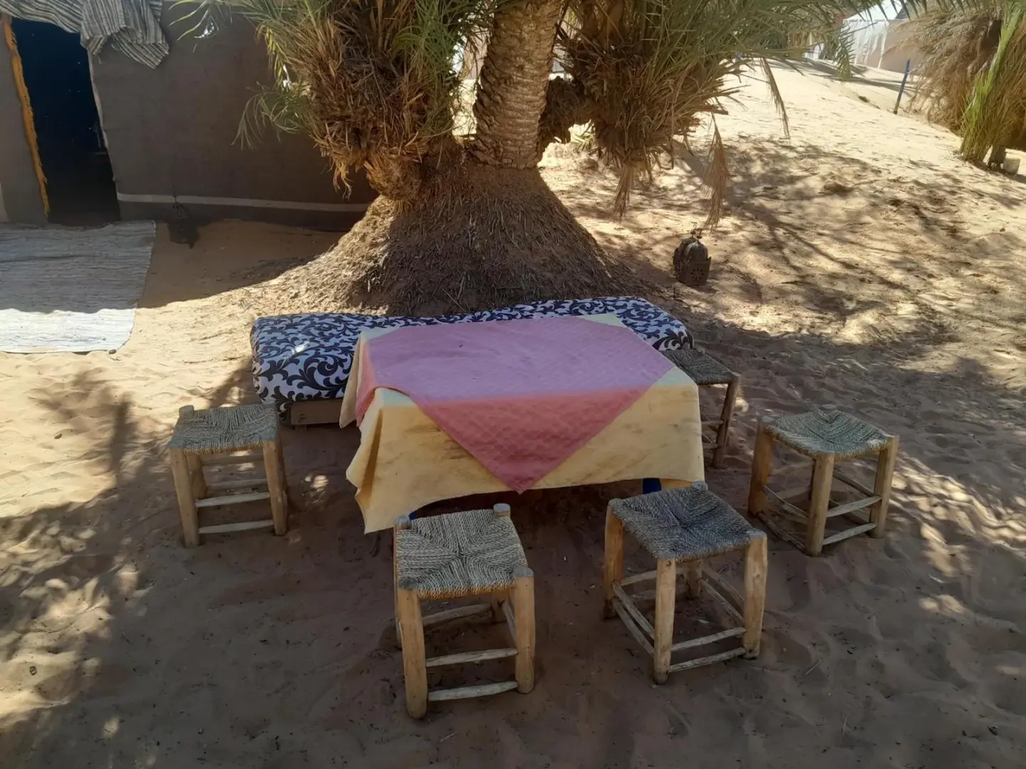 Oasis Desert Camp Obira – hôtel à Merzouga, Maroc – une table et des tabourets devant un arbre à Oasis Desert Camp Obira à Merzouga