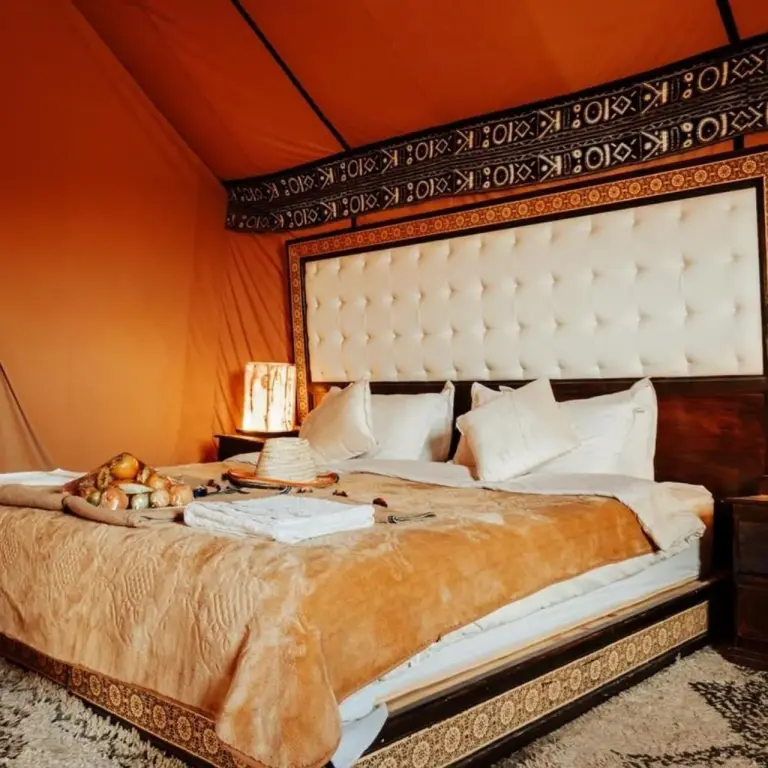 Lujosa cama y montaje de comedor en Oasis Mirage Luxury Camp en Merzouga