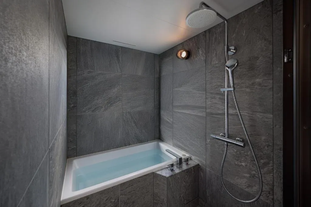 Shower and bathtub in bathroom at One Fukuoka Hotel
