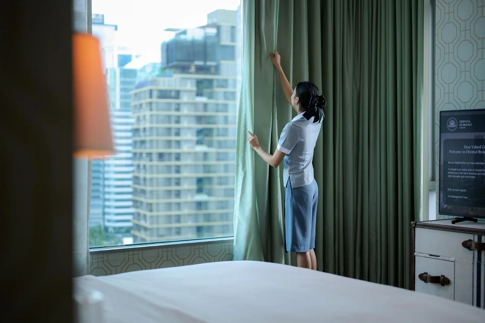 Staff adjusting curtains at Oriental Residence Bangkok