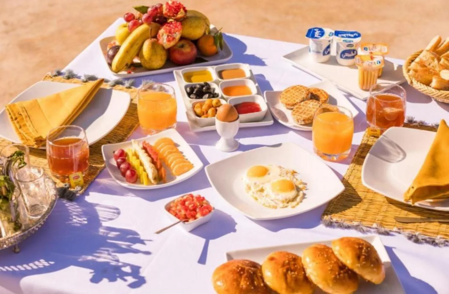 Breakfast spread at Original Luxury Camp in Merzouga with pastries, eggs, fruit, and juice