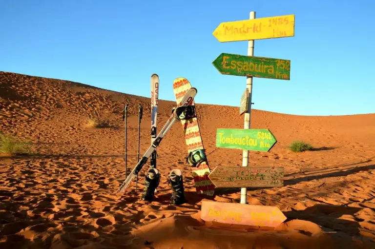 Snowboards and colorful direction signs in the dunes at Original Luxury Camp in Merzouga