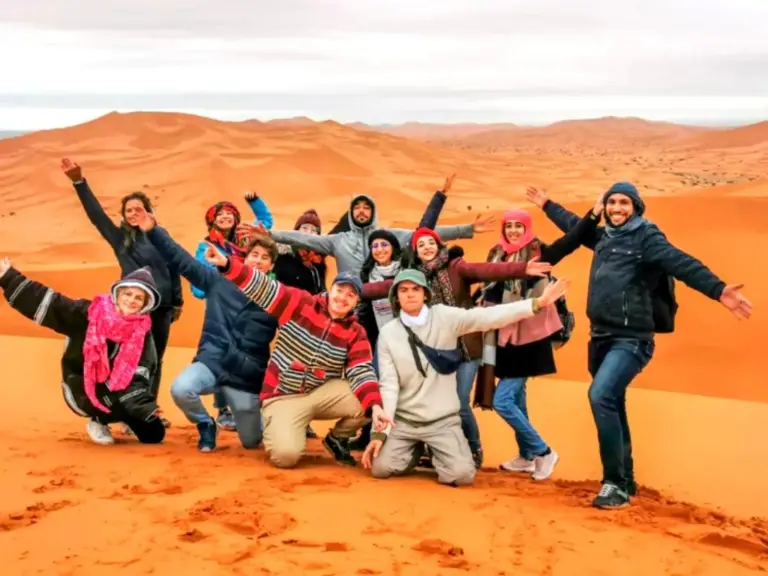 Group of travelers posing on the dunes near Original Luxury Camp in Merzouga desert