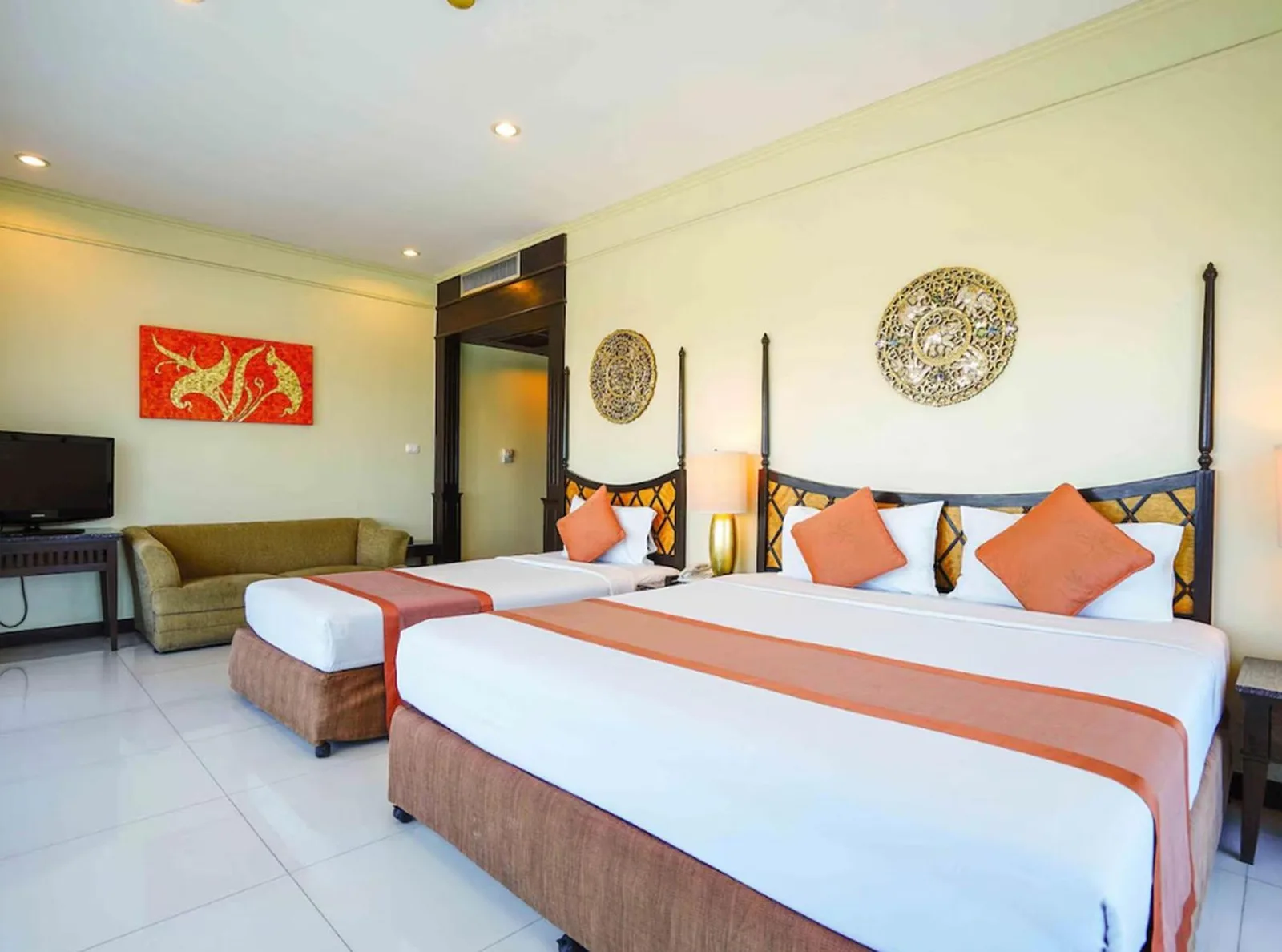 Amplia habitación familiar en Palette Luxe North Pattaya en Pattaya con dos camas, zona de sofá y arte mural decorativo