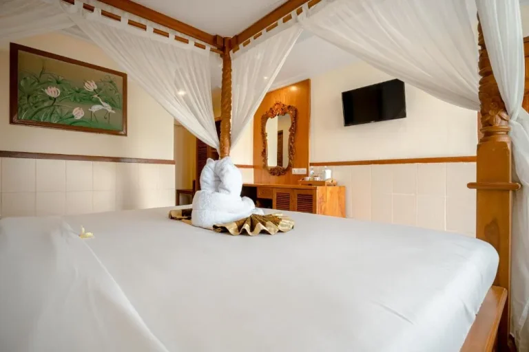 Primer plano de una cama bellamente decorada en una habitación del Palm Beach Hotel Bali.