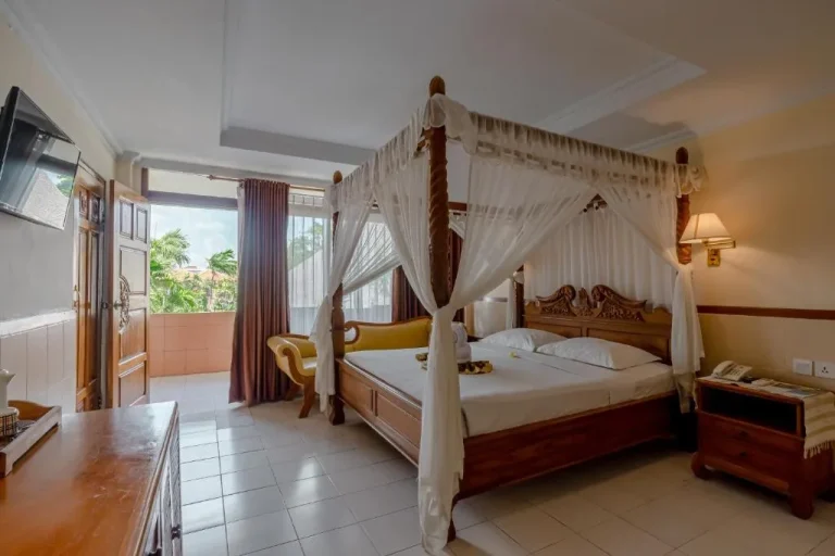 Interior de una Habitación Deluxe en Palm Beach Hotel Bali con una cama con dosel.