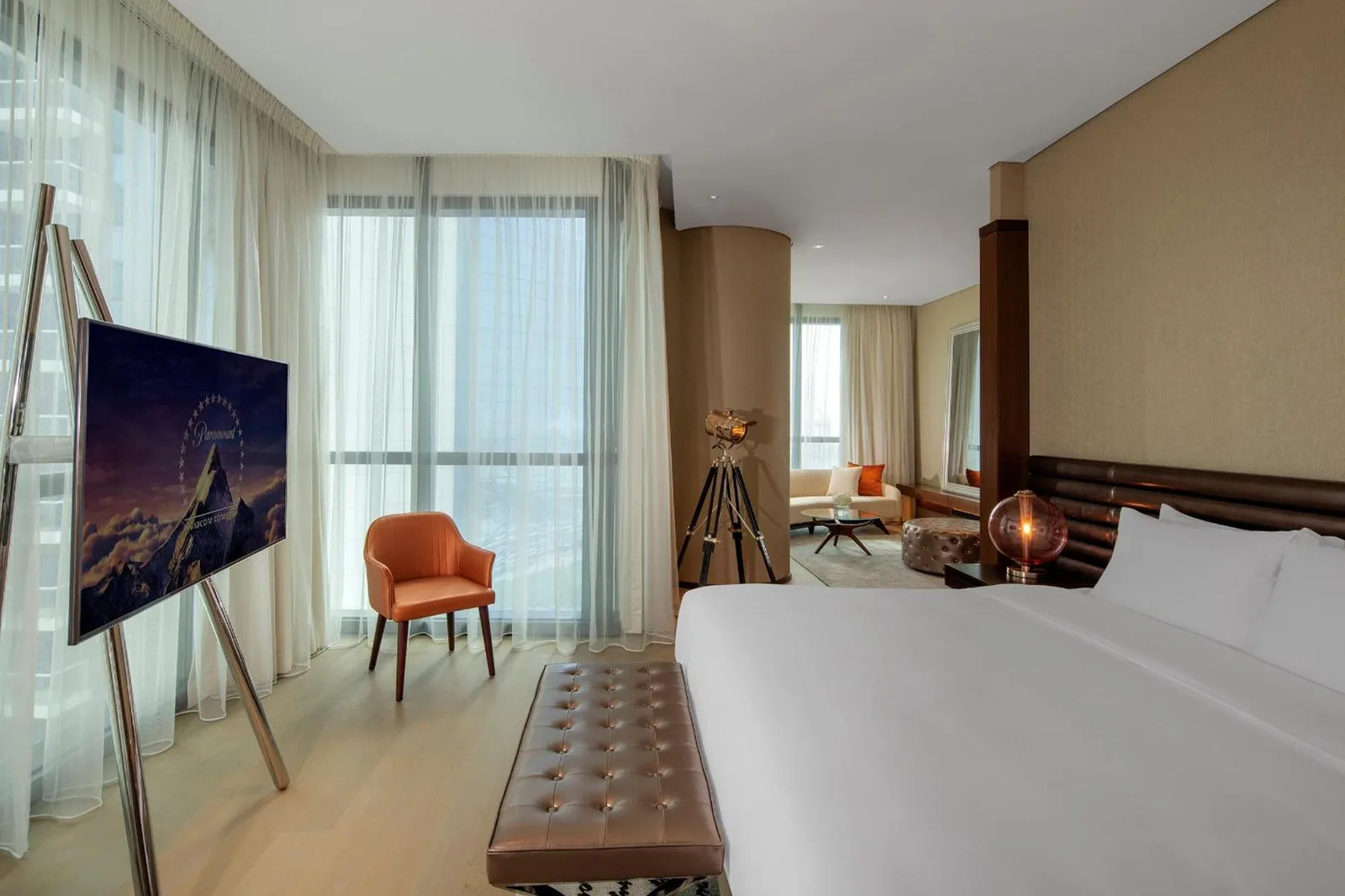 Chambre de suite spacieuse à Paramount Hotel Dubai avec lit, télévision sur chevalet, fauteuil et baies vitrées panoramiques.
