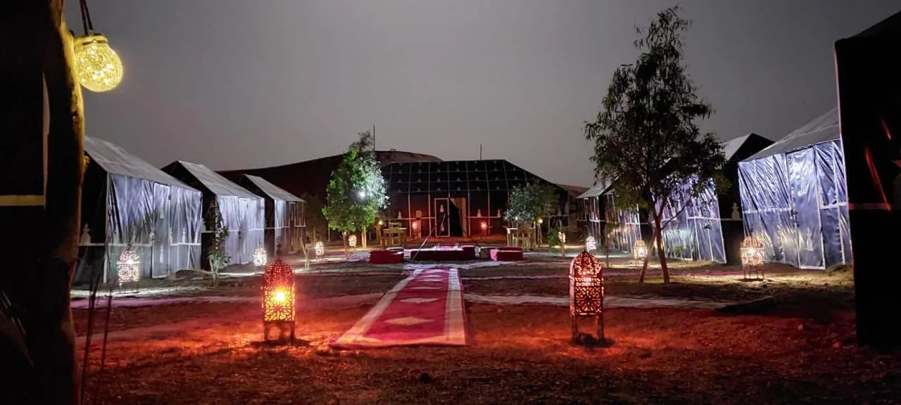 Night view of Planet Sahara Camp in Merzouga illuminated with lanterns and lights