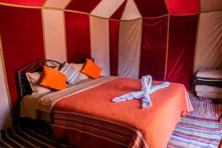 Double bed room inside Planet Sahara Camp in Merzouga with colorful textiles