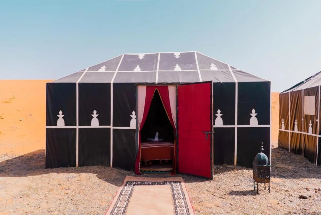 Guest tent entrance at Planet Sahara Camp in Merzouga with red doors and desert path