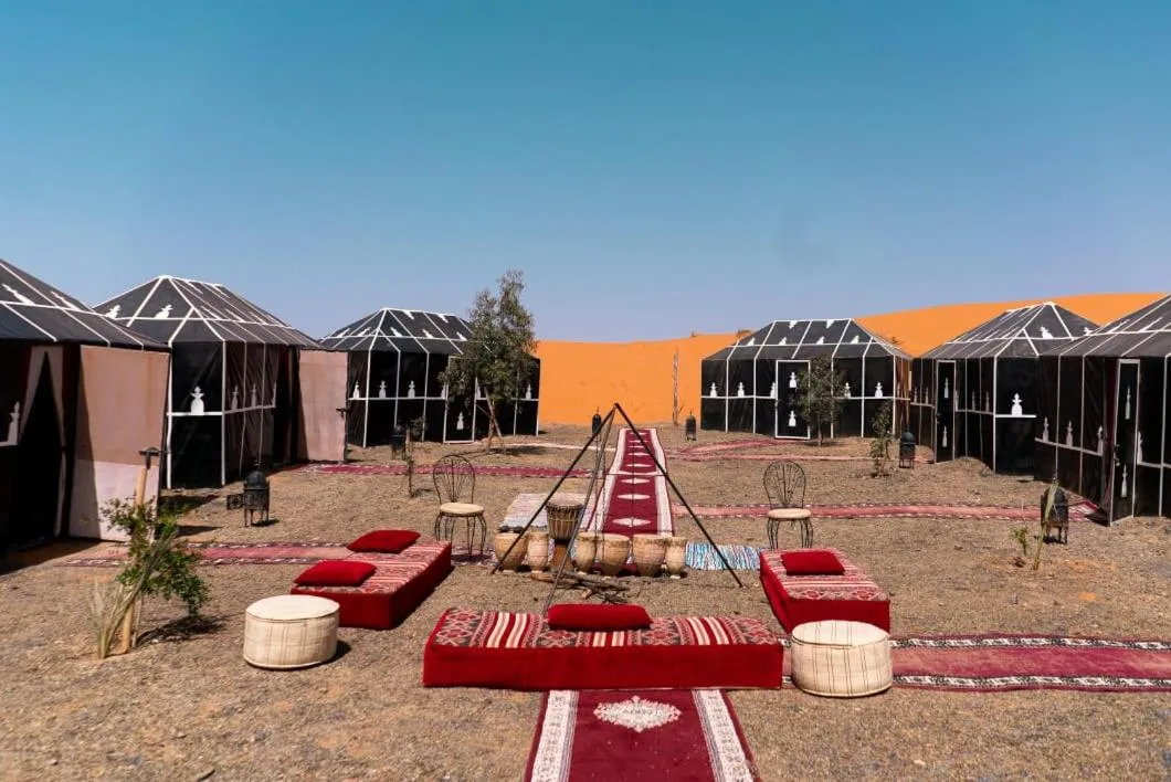 Outdoor lounge area at Planet Sahara Camp in Merzouga with red seating and desert decor
