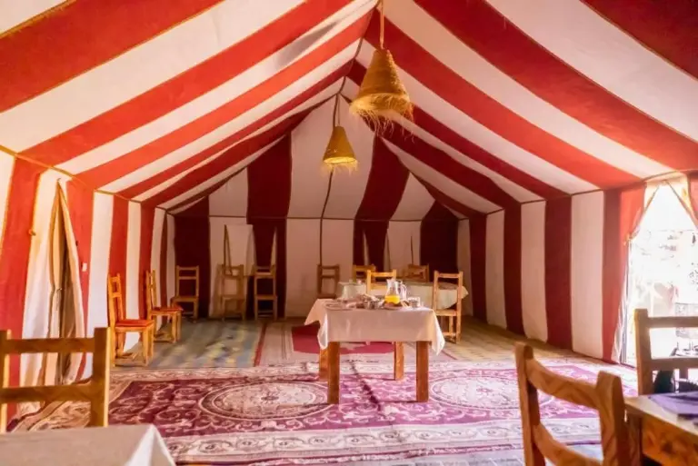 Restaurant tent interior at Planet Sahara Camp in Merzouga with striped fabric and tables