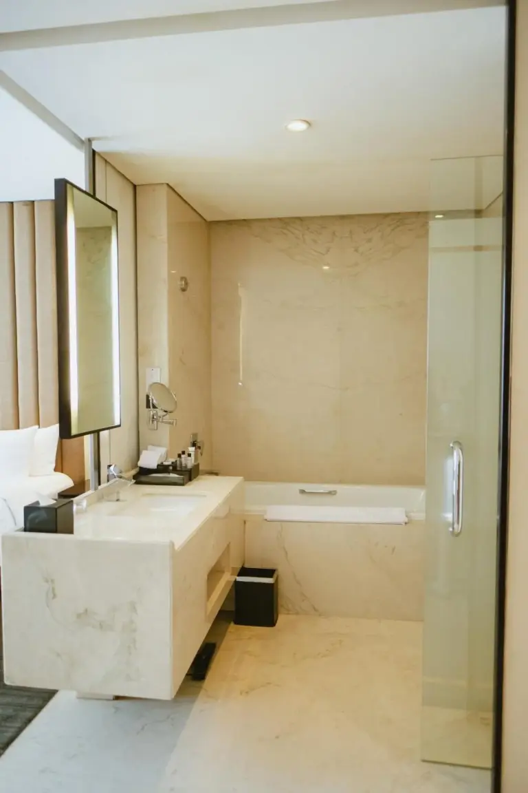Baño elegante en PO Hotel Semarang en Semarang con bañera, tocador y cabina de ducha de cristal.