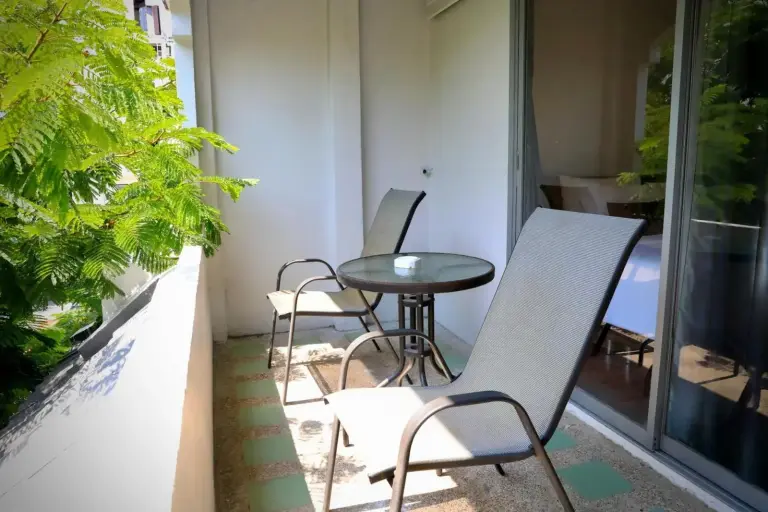 Balcon privé de Pooh Beach Resort & Spa à Pattaya avec fauteuils et petite table