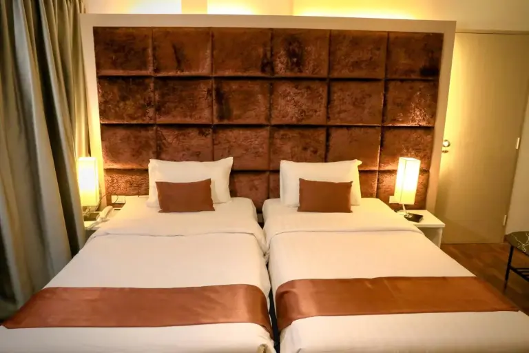 Chambre twin de Pooh Beach Resort & Spa à Pattaya avec tête de lit capitonnée et lampes de chevet