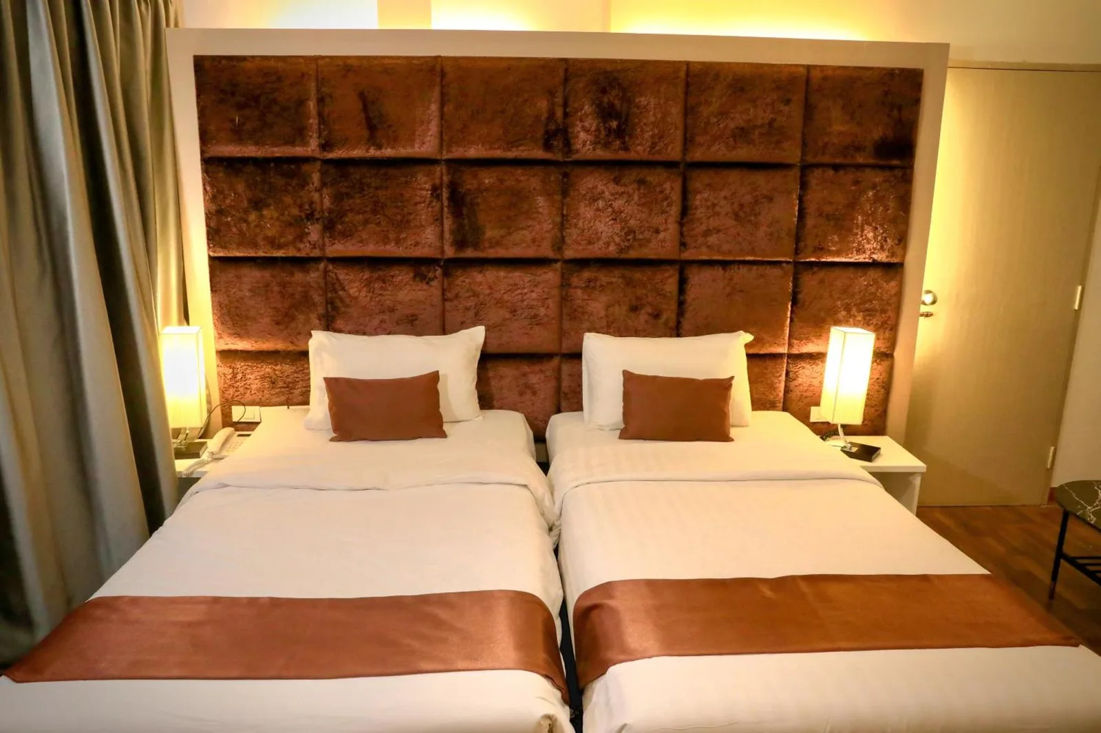 Chambre twin de Pooh Beach Resort & Spa à Pattaya avec tête de lit capitonnée et lampes de chevet