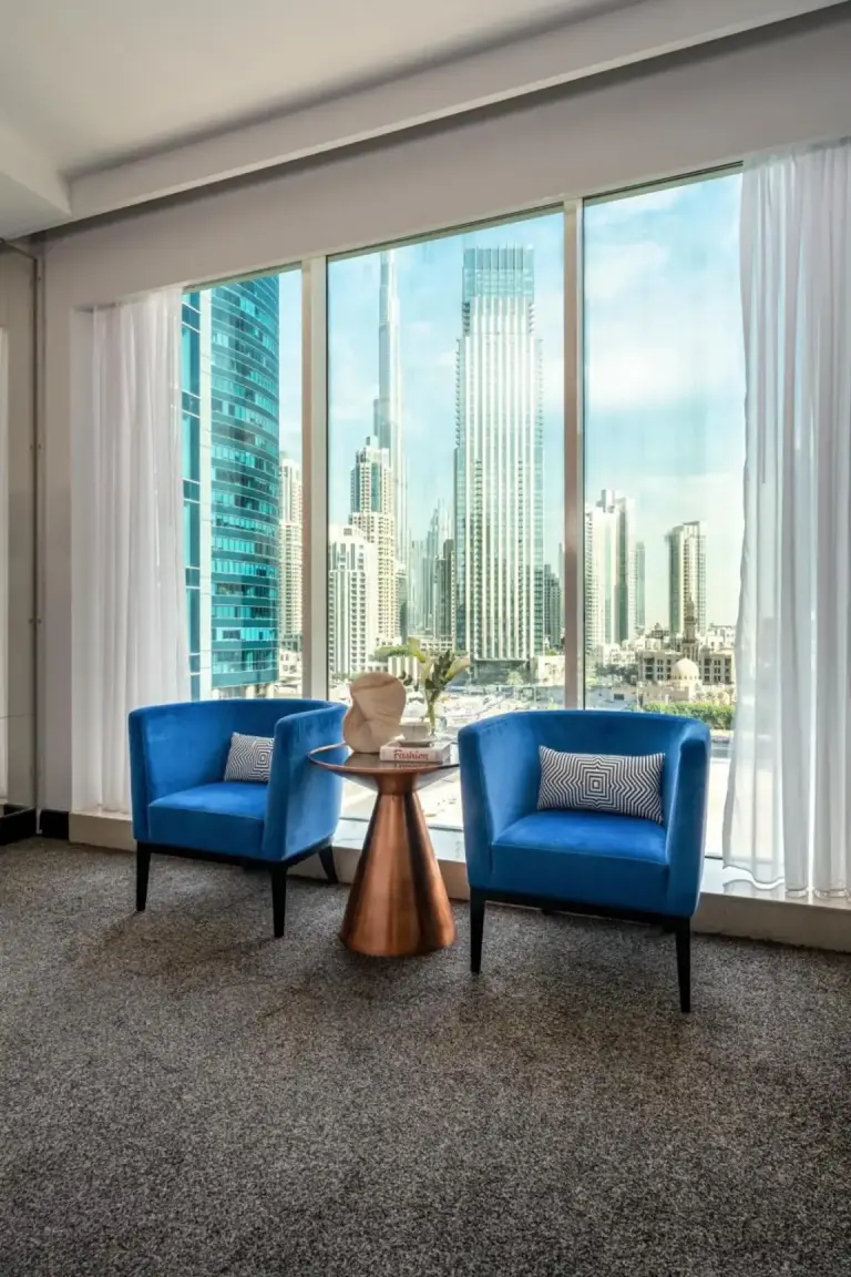 Zona de asientos panorámica en Pullman Dubai Downtown en Dubai con dos sillas azules y vistas al skyline