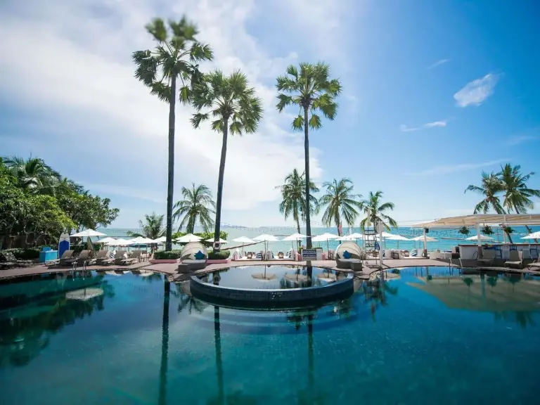 Pullman Pattaya Hotel G – hôtel à Pattaya, Thaïlande – une grande piscine avec des palmiers et des chaises au Pullman Pattaya Hotel G à Pattaya North