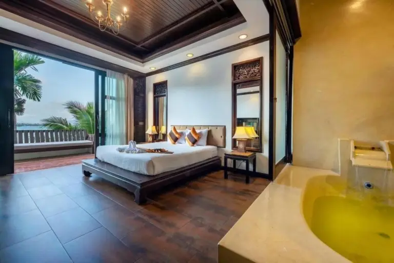 Elegant king bedroom at Racha Kiri Resort & Spa in Khanom, Nakhon Si Thammarat, with wood flooring and a bathroom suite.