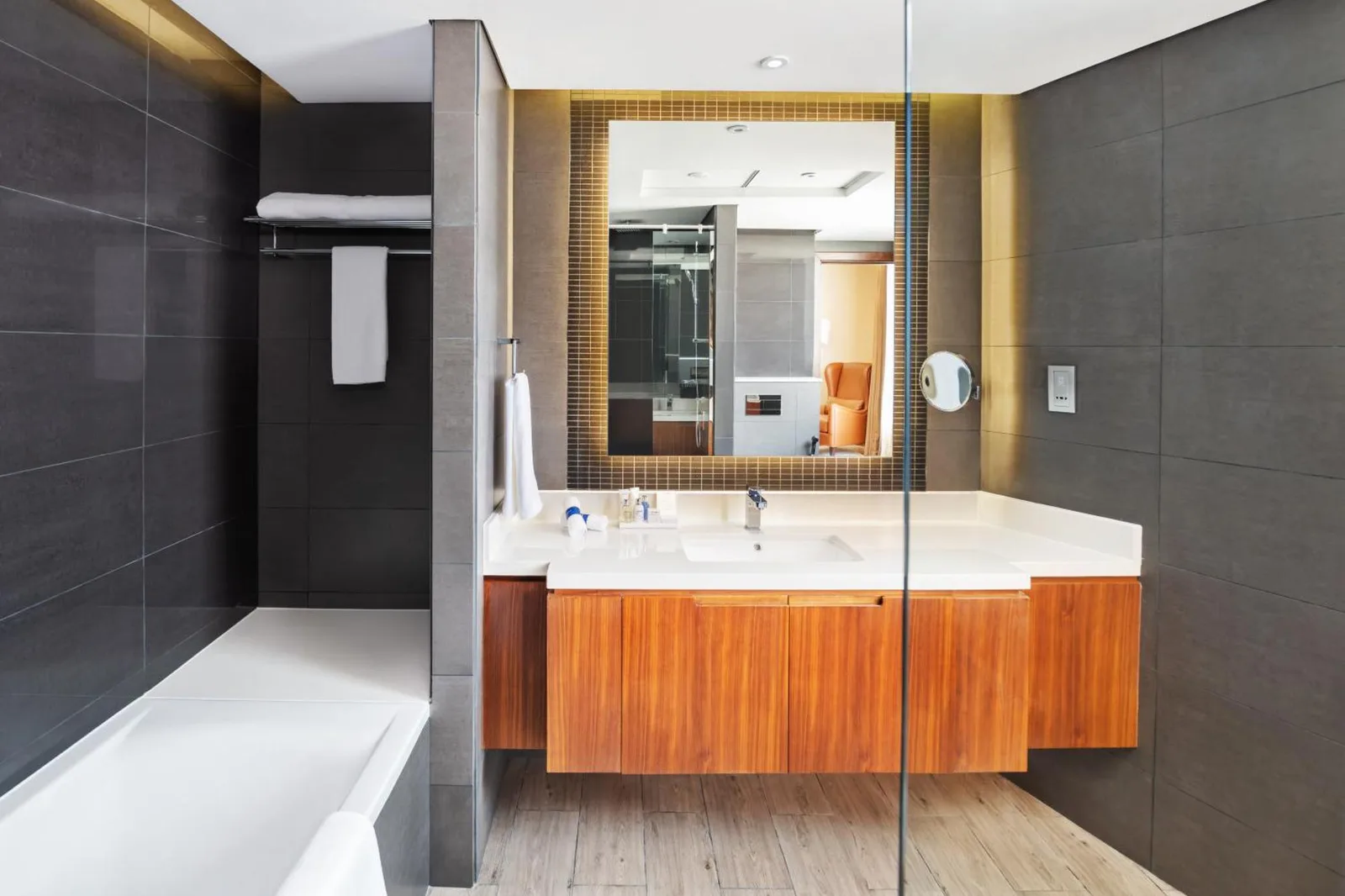 Modern bathroom at Radisson Blu Hotel, Dubai Canal View with a bathtub, vanity, and large mirror