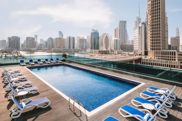 Rooftop pool deck at Radisson Blu Hotel, Dubai Canal View with sun loungers and Dubai skyline views