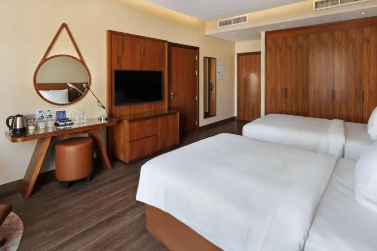 Twin guest room at Radisson Blu Hotel, Dubai Canal View with two beds, TV, and wood-paneled storage