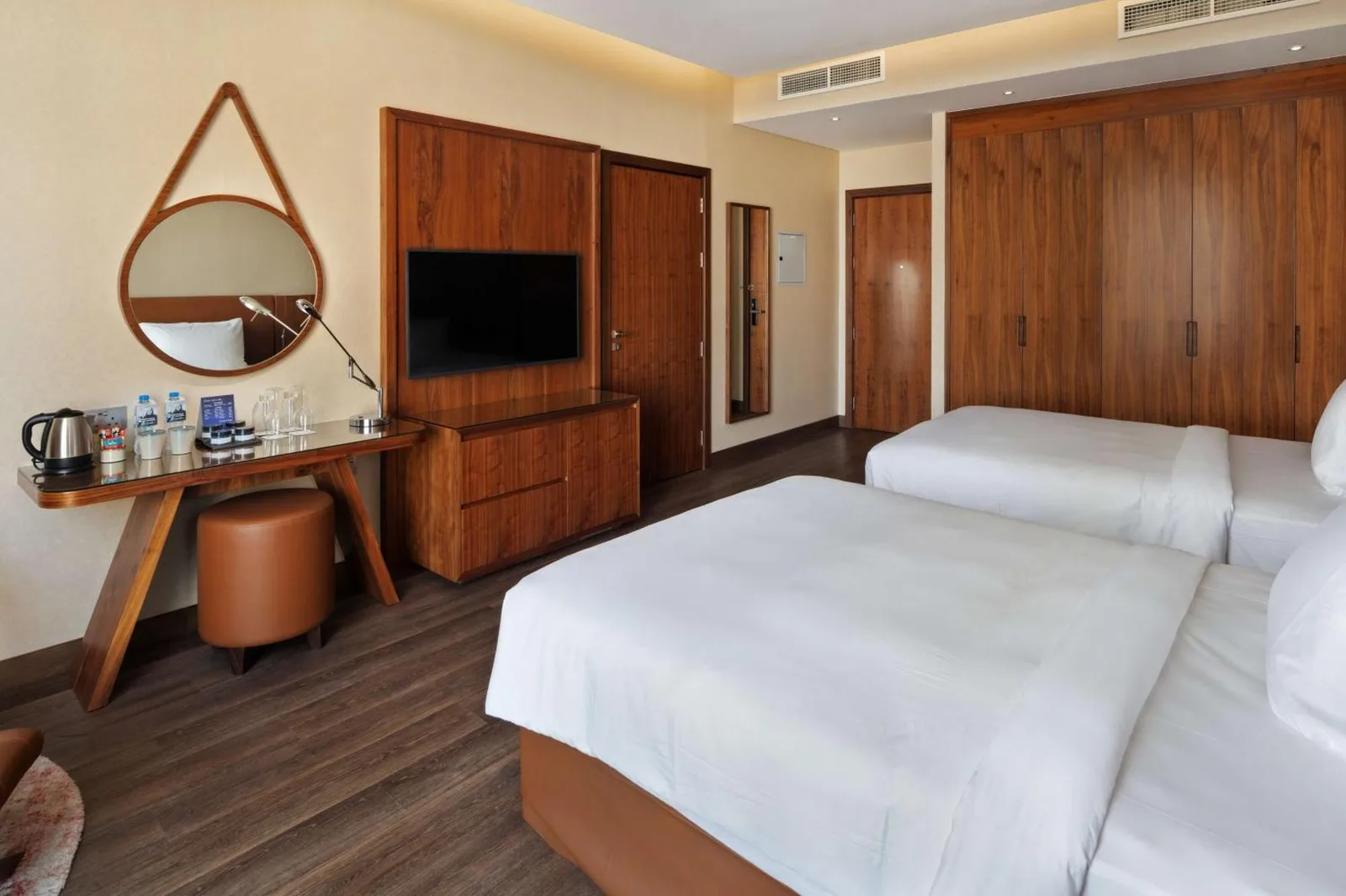Twin guest room at Radisson Blu Hotel, Dubai Canal View with two beds, TV, and wood-paneled storage