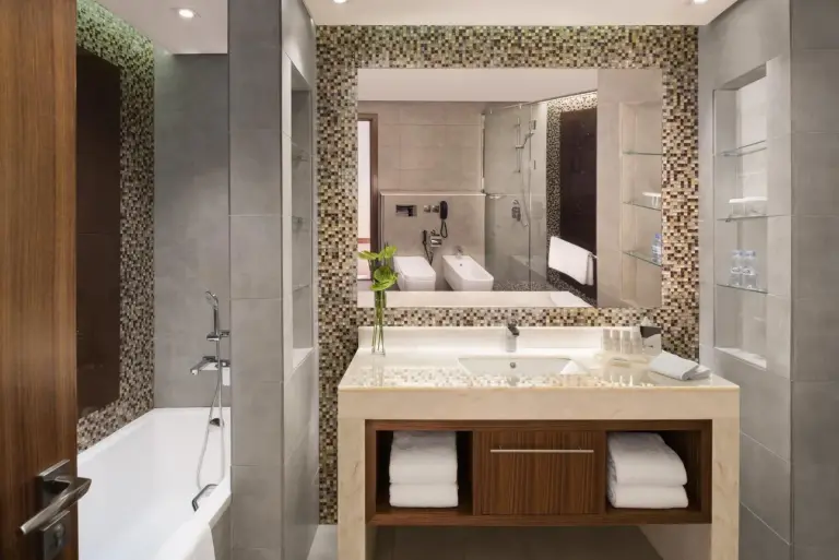 Baño en Radisson Blu Hotel, Dubai Waterfront en Dubai con bañera, lavabo con mueble, espejo y estantes de almacenaje