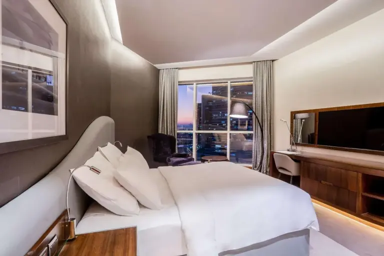 Habitación de huéspedes en Radisson Blu Hotel, Dubai Waterfront en Dubai con cama king, ventana con vistas a la ciudad y asientos contemporáneos
