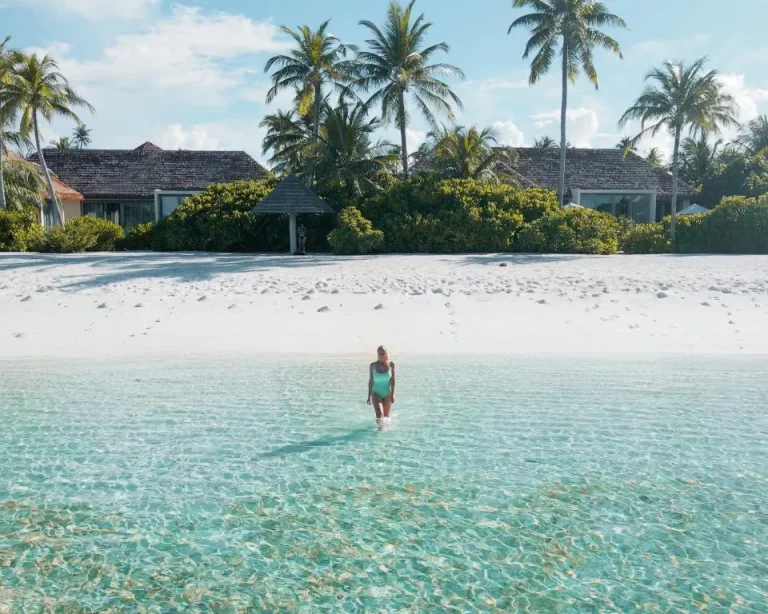 Femme debout dans l'eau claire à la plage du Radisson Blu Resort Maldives