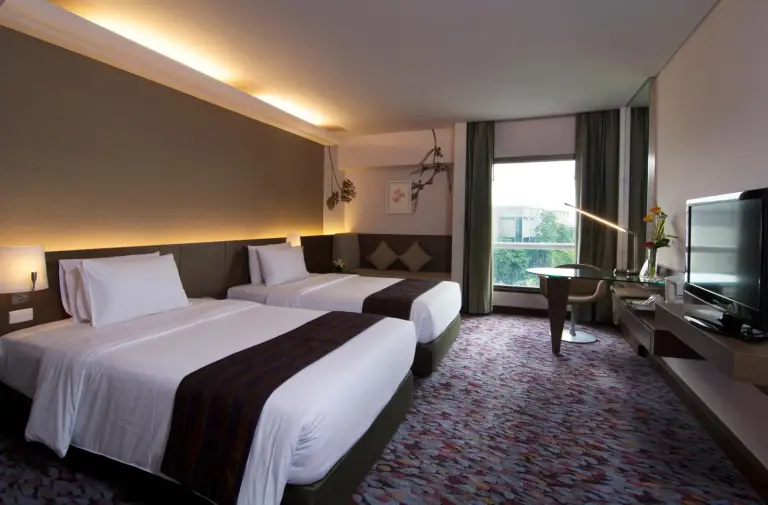 Dormitorio twin en Rama Gardens Hotel Bangkok con dos camas, TV y decoración moderna