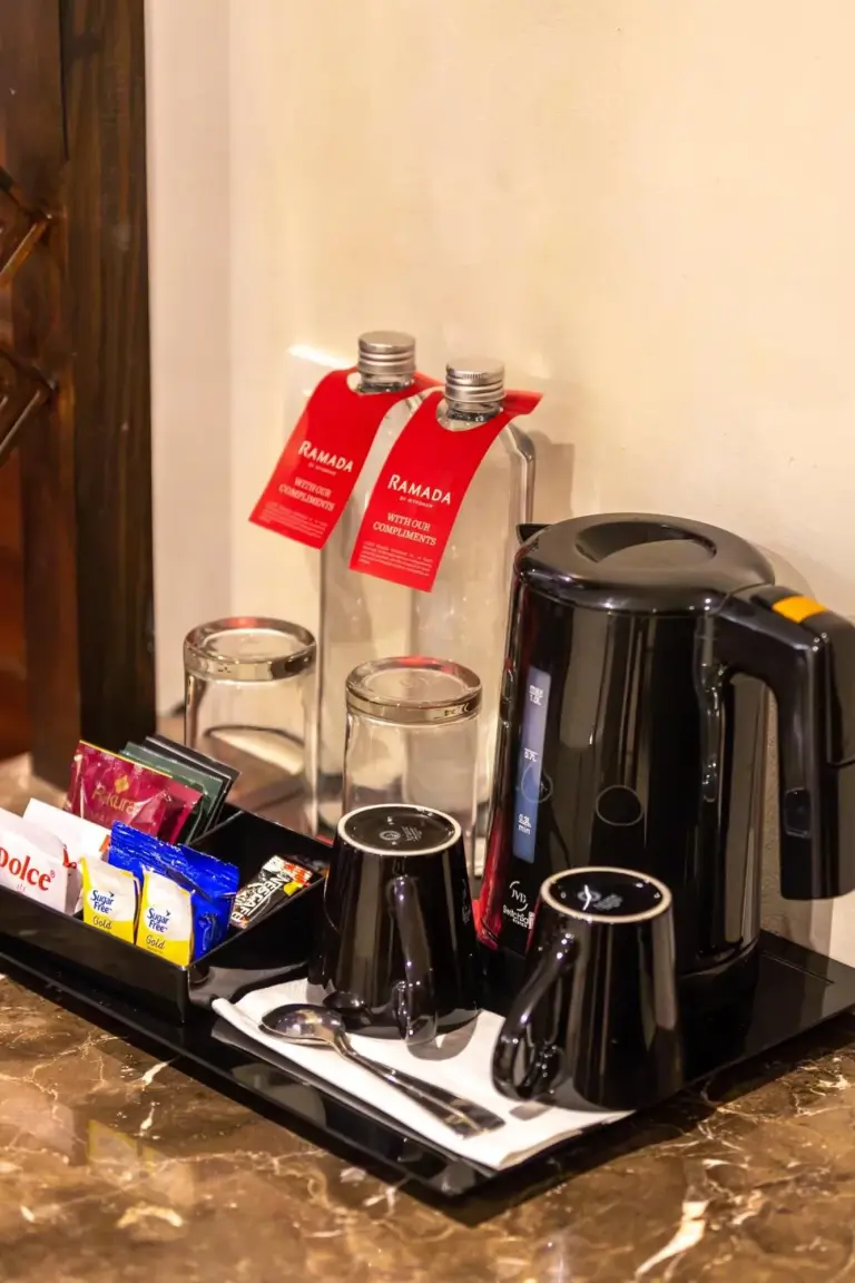 Espace thé et café dans la chambre au Ramada by Wyndham Kathmandu Dhumbarahi à Kathmandu avec bouilloire, tasses et boissons.