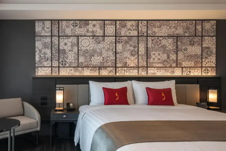 King bed with decorative headboard in a room at Ramada Plaza by Wyndham Chao Fah Phuket