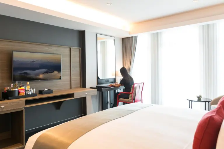 Guest room desk area with seated person at Ramada Plaza by Wyndham Chao Fah Phuket