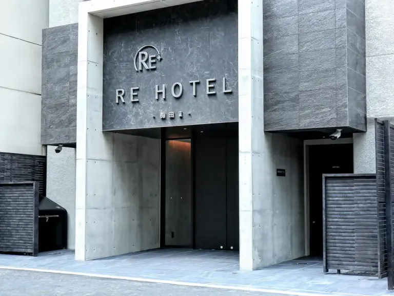 Exterior entrance of RE Hotel Umeda-2 in Osaka with modern concrete facade and hotel signage.