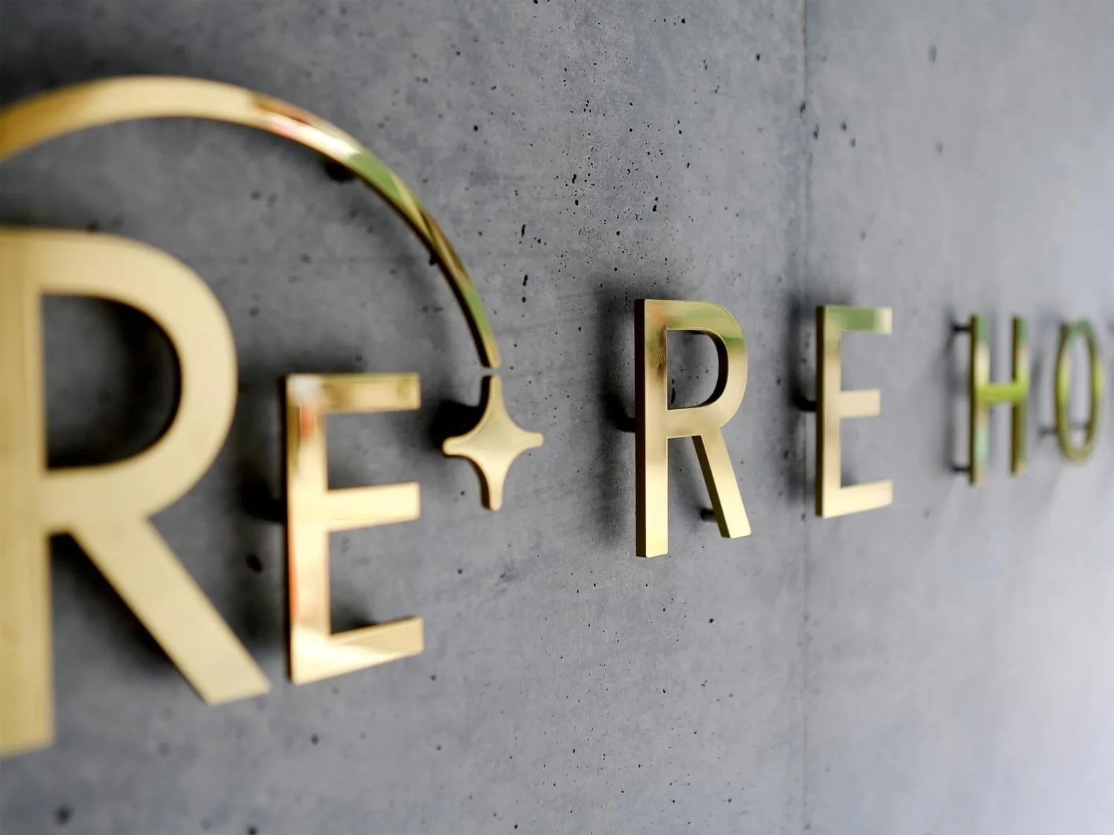 Close-up of gold RE Hotel signage on a concrete wall at RE Hotel Umeda-2 Osaka.