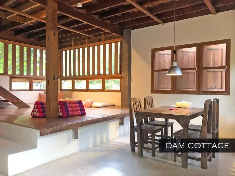 Ess- und Wohnbereich der Dam Cottage im Resort Hoshihana Chiang Mai mit rustikalem Holzdesign