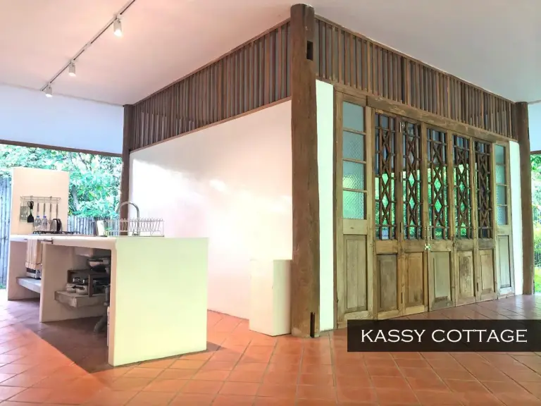 Interior de Kassy Cottage en Resort Hoshihana Chiang Mai con cocina, puertas de madera y suelo de baldosas