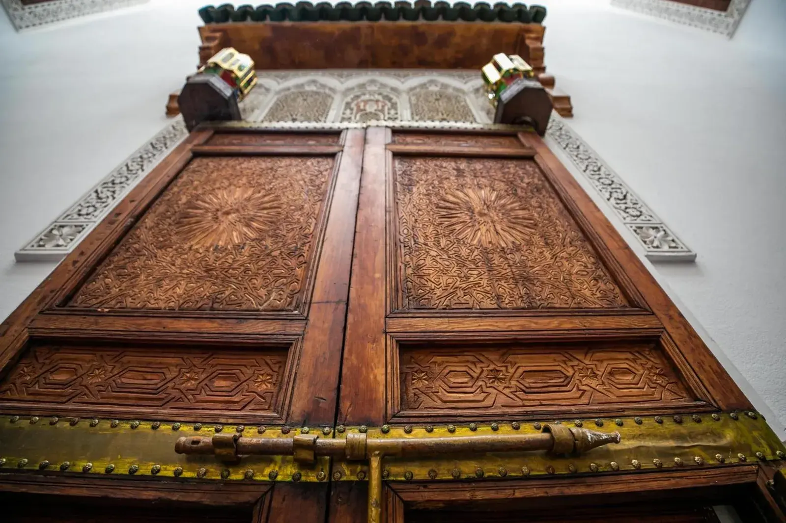 Close-up of ornate carved wooden doors at Riad Arabella in Fes with traditional Moroccan craftsmanship.