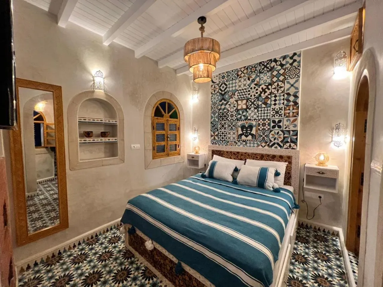 Dormitorio de huéspedes en Riad dar el hania en Essaouira con cama verde azulado, baldosas estampadas y pequeños nichos empotrados