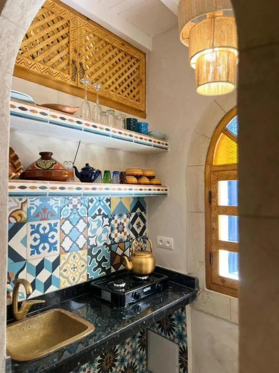 Kitchenette compacta en Riad dar el hania en Essaouira con salpicadero estampado, fregadero y estantes abiertos